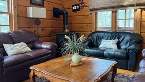 Een gezellig chaletinterieur met twee leren banken, een houten bijzettafeltje en een rustieke inrichting.