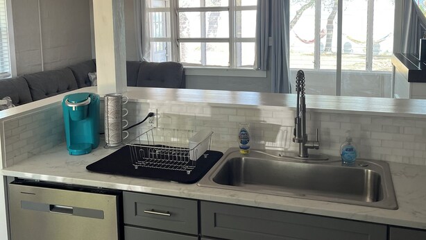Una cocina moderna con un lavamanos de acero inoxidable, una cafetera y un escurreplatos.