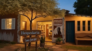 A building with a sign reading "Hespedaria Sao Jorge" and a poster with a silhouette of a person. - Hospedaria & Galeria de Arte São Jorge  (Alto Paraíso de Goiás)