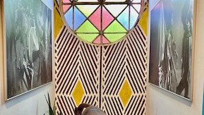 A hallway with a patterned wall, a decorative window, and a sculpture of a cat. - Hospedaria & Galeria de Arte São Jorge  (Alto Paraíso de Goiás)