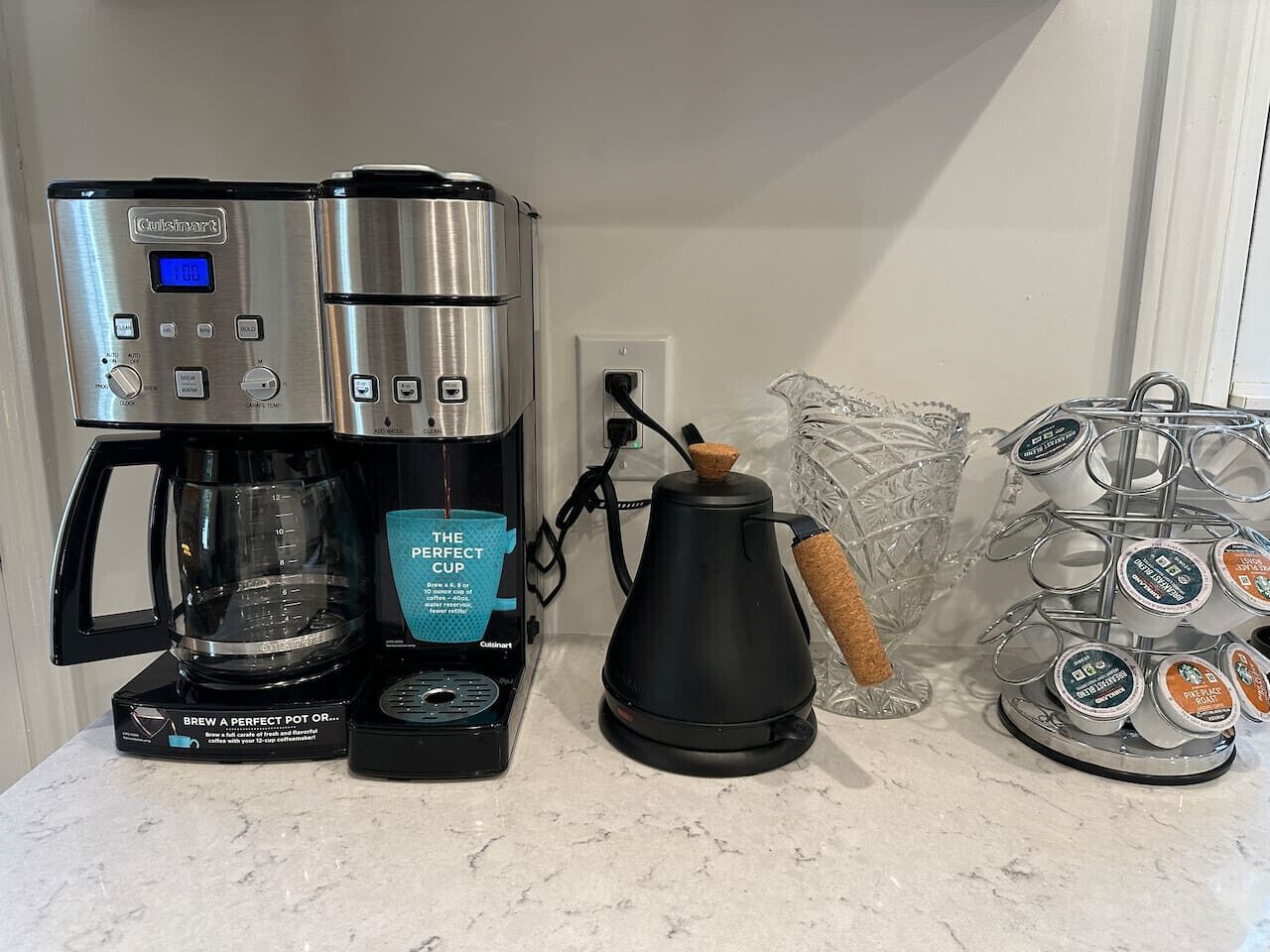 Une machine à café, une bouilloire et un porte-tasses sur un plan de travail de cuisine.