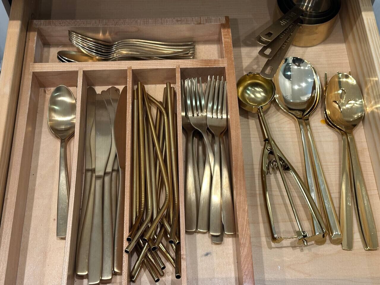 A drawer with neatly organized cutlery including spoons, forks, and knives.