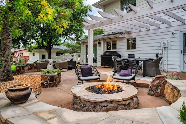 An outdoor patio with stone fire pit, wicker furniture, and a pergola. - Peaceful Retreat Near Downtown Boulder – 1 Acre of Fun & Relaxation (Boulder)