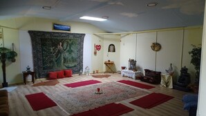 Una sala de estar con un tapiz grande, alfombras rojas, una estatua y una chimenea.