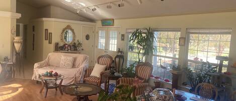 A cozy living room with a ceiling fan, a dining table with a glass top, and various decorative items.