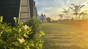 A modern building with a unique triangular design, a grassy area with stepping stones, and a clear sky. - Romnea Moon Resort (Krong Saen Monourom)