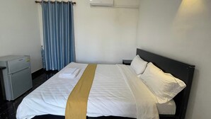 A hotel room with a bed, a nightstand, an air conditioning unit, a window with curtains, and a wall-mounted light fixture. - Romnea Moon Resort (Krong Saen Monourom)