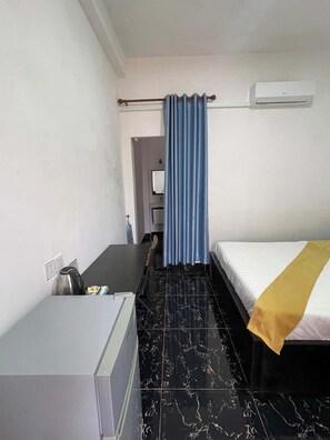 A small hotel room with a bed, a desk, a kettle, and a curtain. - Romnea Moon Resort (Krong Saen Monourom)