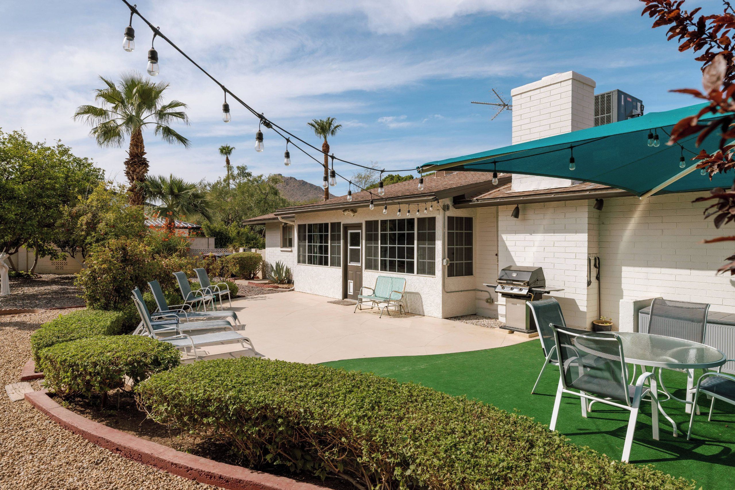A residential property with a covered patio, outdoor seating, and a barbecue area.