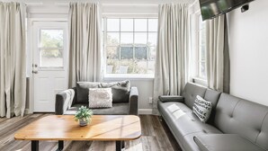 A living room with a sofa, a coffee table, and a TV mounted on the wall.