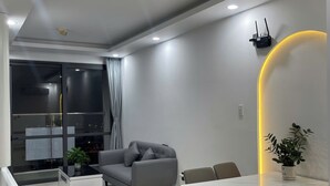 Een moderne woonkamer met een grijze bank, een eettafel met stoelen en een potplant.