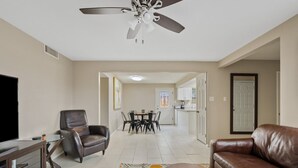 A living room with a TV, leather chairs, a dining area, and a kitchen in the background. - Spacious 2BR Condo by Downtown Mesa Free Parking (Mesa)