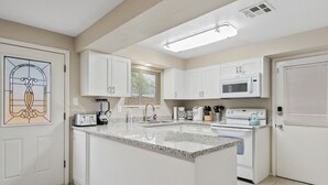 A modern kitchen with white cabinets, a granite countertop, a built-in microwave, and a coffee maker. - Spacious 2BR Condo by Downtown Mesa Free Parking (Mesa)