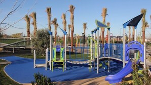 A playground with climbing structures, slides, and a blue rubberized surface. - Spacious 2BR Condo by Downtown Mesa Free Parking (Mesa)