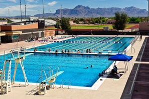 Una piscina con plataformas de salto, zona para espectadores y montañas al fondo.