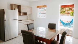 A modern kitchen with a refrigerator, cabinets, and a dining table with chairs. - Casa del Sol (Noord)