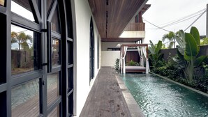 Ein modernes Gebäude mit großen Fenstern, einer Holzterrasse und einem Pool.