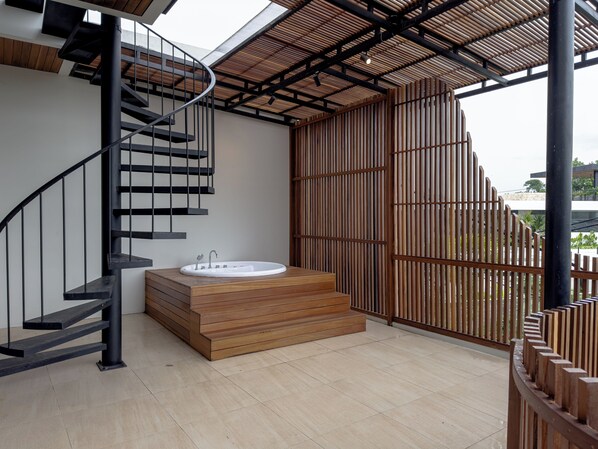 Un baño moderno con una bañera de madera, una escalera espiral negra y un ventanal grande.