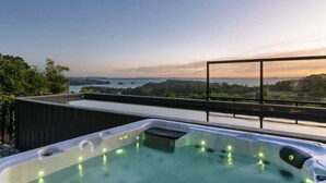 Terraza en la azotea con jacuzzi y vistas panorámicas al agua y colinas.