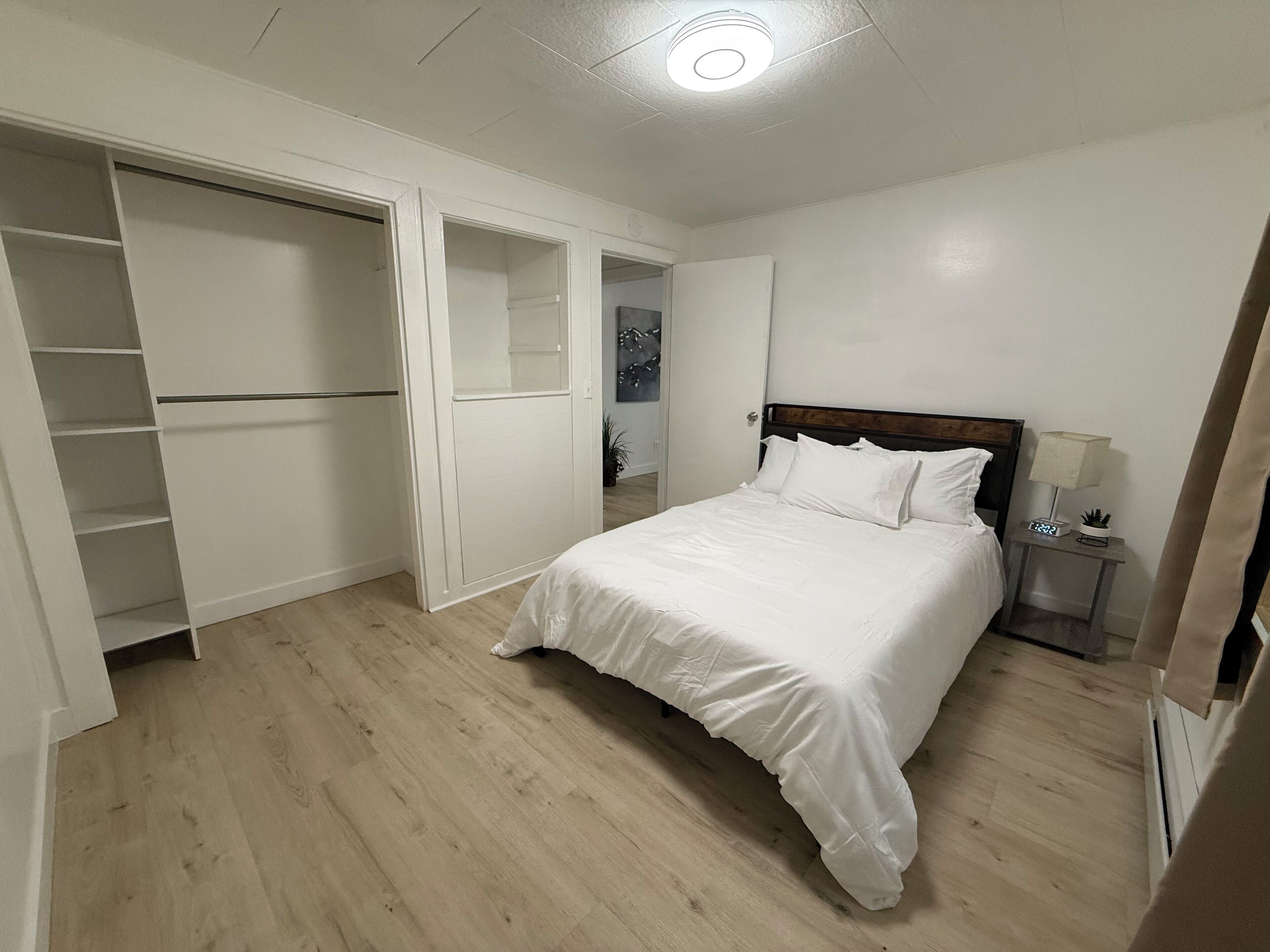 Une chambre à coucher avec un lit, une table de chevet, une lampe et une armoire.