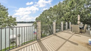 A deck with a view of a lake, a flag, and outdoor furniture. - Morehead Retreat on 75 ft of East Lake Okoboji (Spirit Lake)