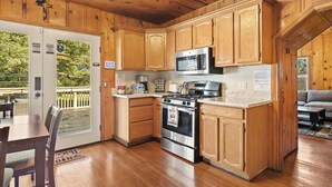 A wooden cabin kitchen with a stove, microwave, and wooden cabinets.