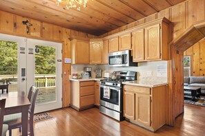 A wooden cabin kitchen with a stove, microwave, and wooden cabinets.