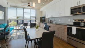 Een moderne keuken met witte kastjes, roestvrijstalen apparatuur en een eetgedeelte met een tafel en stoelen.