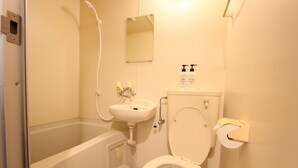 Un baño con bañera, inodoro, lavamanos y espejo.