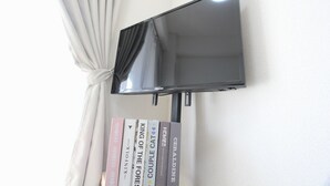 Un televisor de pantalla plana montado en la pared, con una cortina que lo cubre parcialmente.