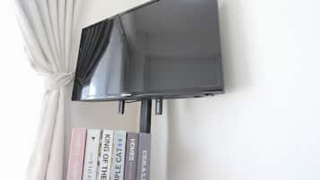 A flat-screen TV mounted on a wall with a curtain partially covering it.