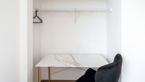 Een minimalistisch ingerichte kamer met een witte marmeren tafel, een zwarte stoel en een witte wand met een witte plank.