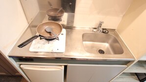A compact kitchen with a stainless steel sink, a white countertop, and a built-in dishwasher.