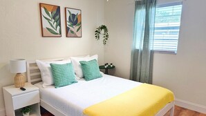 Ein ordentlich eingerichtetes Schlafzimmer mit Bett, Nachttisch, Lampe und einer kleinen Topfpflanze.