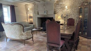 A rustic dining room with a stone fireplace, wooden furniture, and a traditional clock. - 3Bedrooms-Sleeps6-WiFi-Fireplace (Ceaux-en-Loudun)