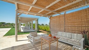 Une terrasse extérieure dotée d’un espace salon abrité, d’une table et offrant une vue sur le paysage environnant.