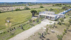 Une propriété rurale comprenant un grand champ ouvert, un petit bâtiment doté d’un toit plat et quelques arbres dispersés.