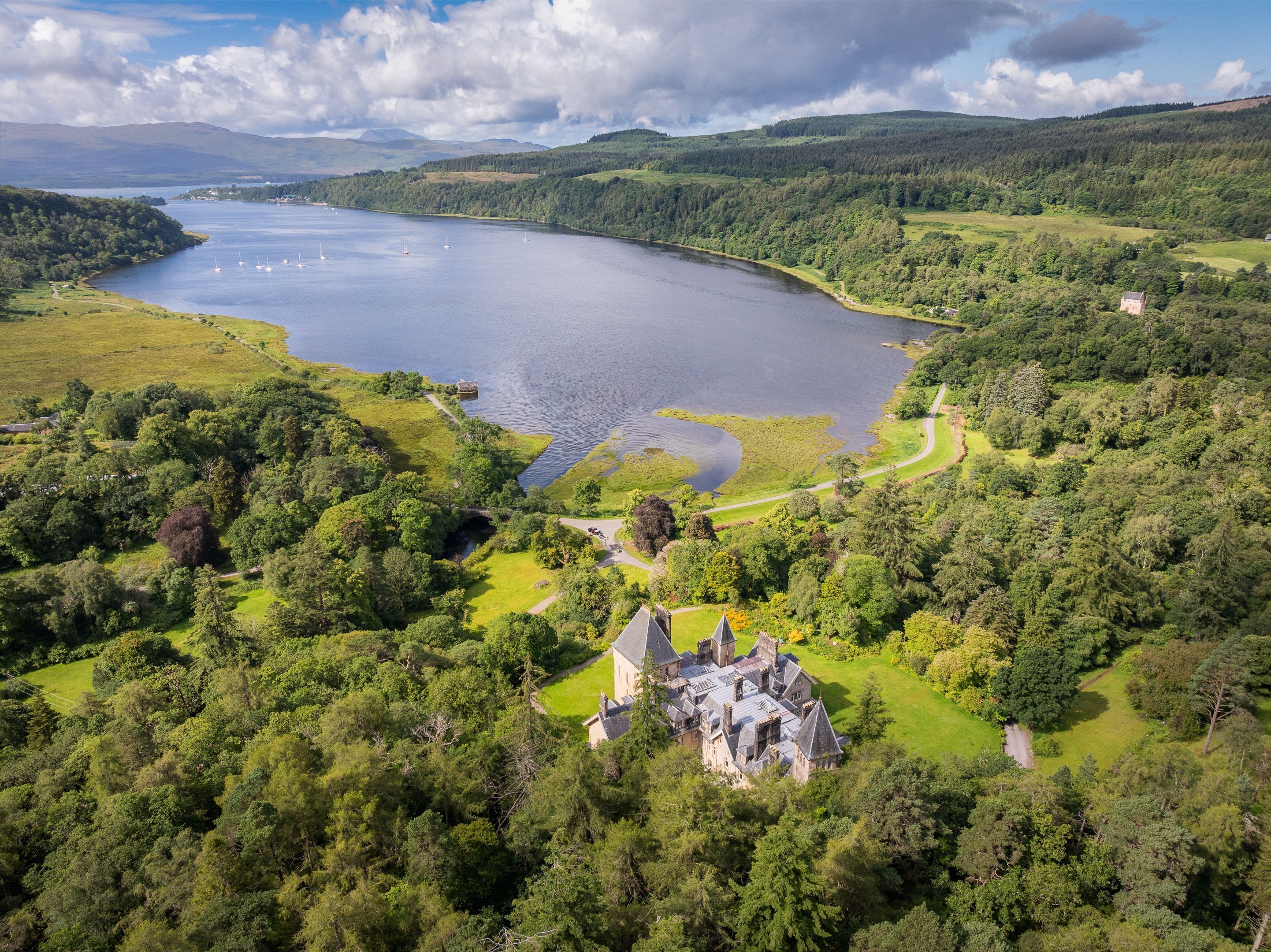 Un bâtiment historique entouré d’une végétation luxuriante et bordé d’un lac.