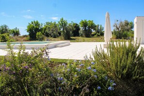 Area piscina con scalini che conducono a un edificio bianco, immersa nel verde e alberi.