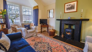 A cozy living room with a fireplace, a television, and a bookshelf.
