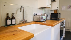 A kitchen with a wooden countertop, a white sink, a toaster, and two bottles of hand wash soap.