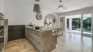 A modern kitchen with a large island, black and white backsplash, and a view to the outdoor patio.
