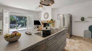 A modern kitchen with a large island, a built-in stove, and a refrigerator.