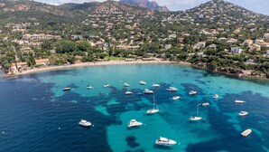 A coastal town with a marina filled with boats, surrounded by hills and residential buildings.