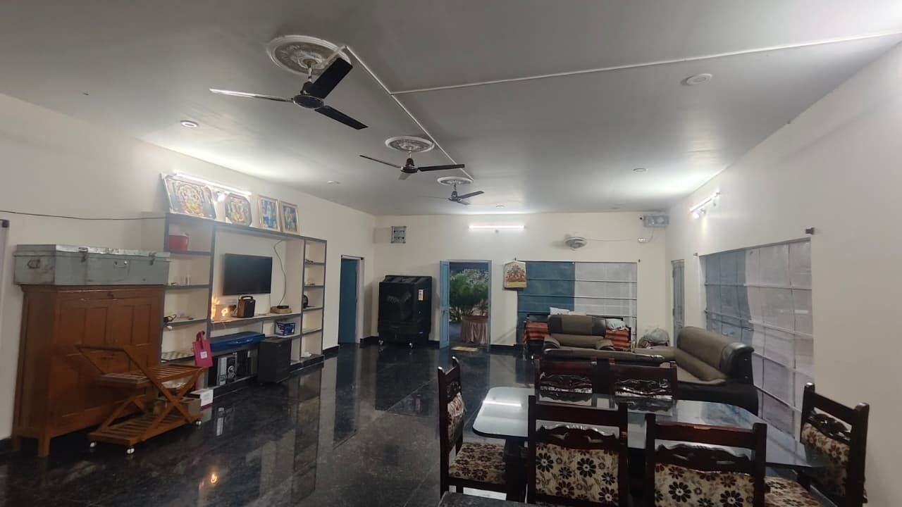A spacious living room with a dining area, ceiling fans, and a television.