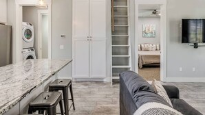 A modern kitchen with a marble countertop, a built-in washing machine, and a staircase leading to a loft bedroom. - Shore Enough | Carlton Landing Lakeview, Up to 18 (Eufaula)