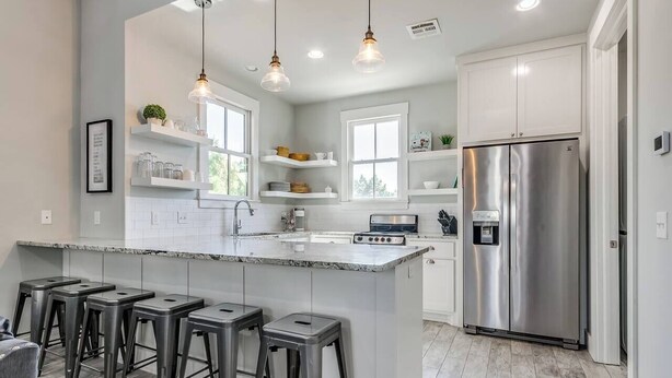 A modern kitchen with a central island, stainless steel appliances, and bar stools. - Shore Enough | Carlton Landing Lakeview, Up to 18 (Eufaula)