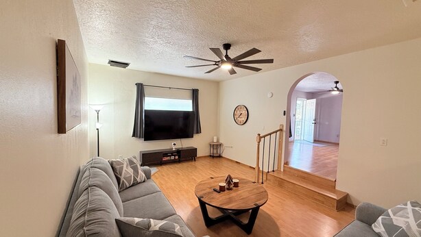 A living room with a sofa, a coffee table, a TV, and a ceiling fan. - 3Br Farmington Home & 75” Smart Tv + Pet Friendly (Farmington)
