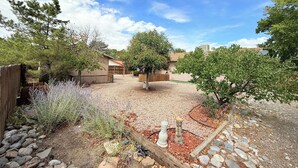 A backyard with a wooden fence, a gravel path, and a variety of plants. - 3Br Farmington Home & 75” Smart Tv + Pet Friendly (Farmington)