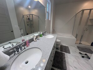 A bathroom with two sinks, a large mirror, a shower, and a bathtub.